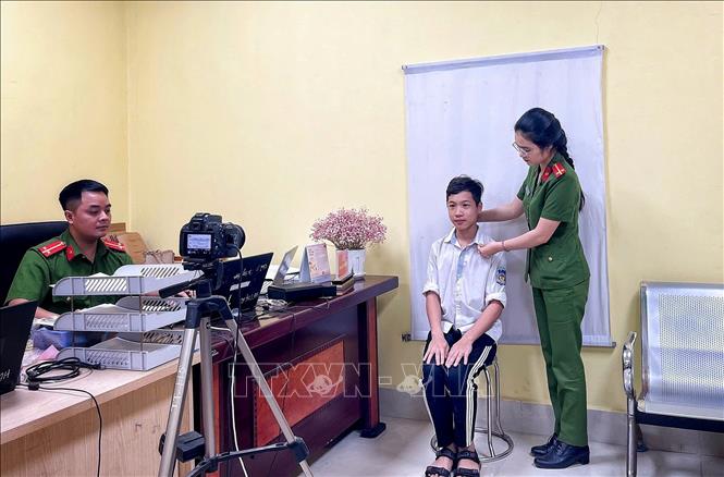 Nữ Công an phường Thuận Thành tận tình hướng dẫn học sinh đến làm CCCD. Ảnh: Danh Lam -TTXVN 