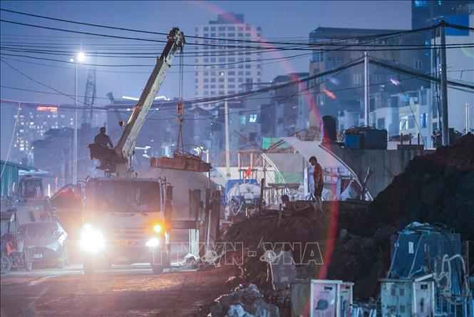 Công nhân cùng máy móc thi công xuyên đêm trên công trường dự án Vành đai 1 đoạn Hoàng Cầu – Voi Phục nhằm đẩy nhanh tiến độ hoàn thành các hạng mục. Ảnh: Lê Đông - TTXVN