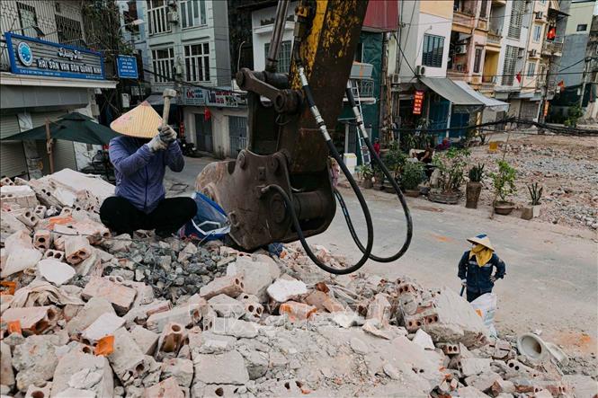 Các công nhân đang thu dọn vật dụng giữa khu vực đang phá dỡ công trình phục vụ dự án mở rộng đường. Ảnh: Phạm Tuấn Anh - TTXVN