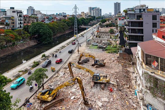 Máy móc hoạt động liên tục trên các khu đất vừa được giải phóng mặt bằng dọc tuyến Tam Trinh. Ảnh: Phạm Tuấn Anh - TTXVN