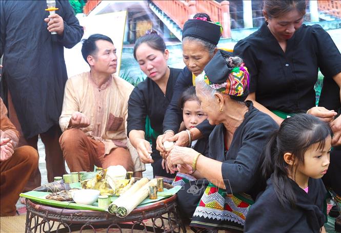 Sau nghi thức cúng, quả trứng gà đã luộc chín trên mâm cúng sẽ được chia cho các em nhỏ có mặt để dự lễ đặt tên, nhập họ và buộc chỉ cổ tay. Ảnh: Xuân Tiến - TTXVN 