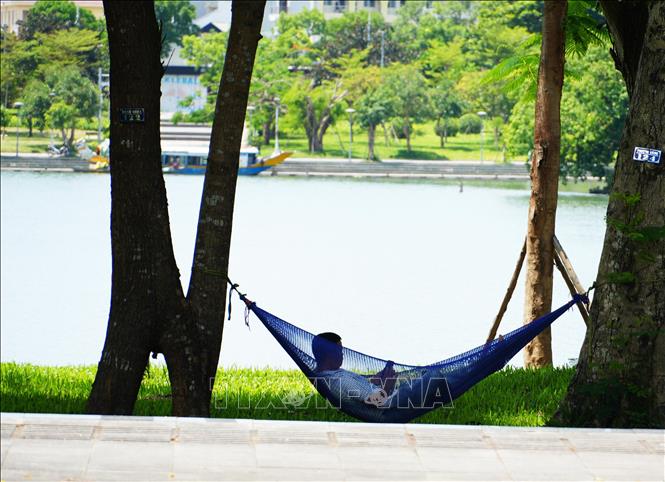 Người dân đến công viên ở bờ Bắc sông Hương, phường Phú Xuân, thành phố Huế để hóng mát, tránh nắng nóng. Ảnh: Nguyên Lý- TTXVN
