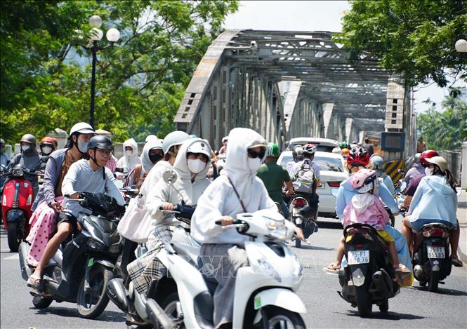 Người dân mặc đồ bảo hộ chống nắng nóng, khi tham gia giao thông ở phía Bắc cầu Trường Tiền, phường Phú Xuân, thành phố Huế. Ảnh: Nguyên Lý- TTXVN