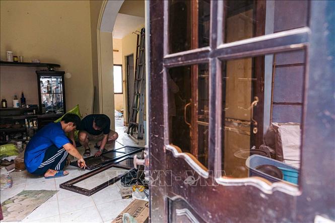 Người dân tranh thủ tháo dỡ cửa và di chuyển đồ đạc khỏi căn nhà nằm trong diện giải phóng mặt bằng. Ảnh: Phạm Tuấn Anh - TTXVN