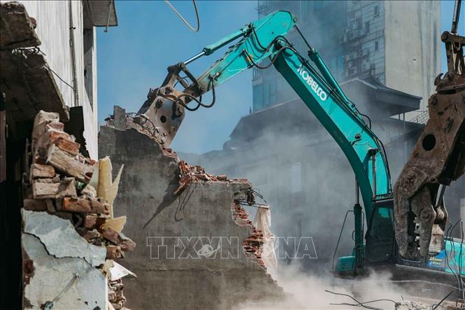 Máy xúc phá vỡ từng mảng tường bê tông trong quá trình tháo dỡ công trình cũ. Ảnh: Phạm Tuấn Anh - TTXVN