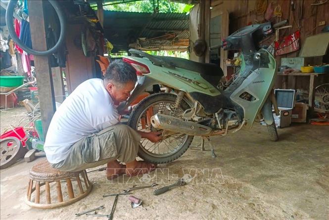 Chủ tiệm sửa chữa xe máy trong bản Na Ngân đang sửa chữa xe máy cho người dân trong bản. Ảnh: Xuân Tiến - TTXVN 