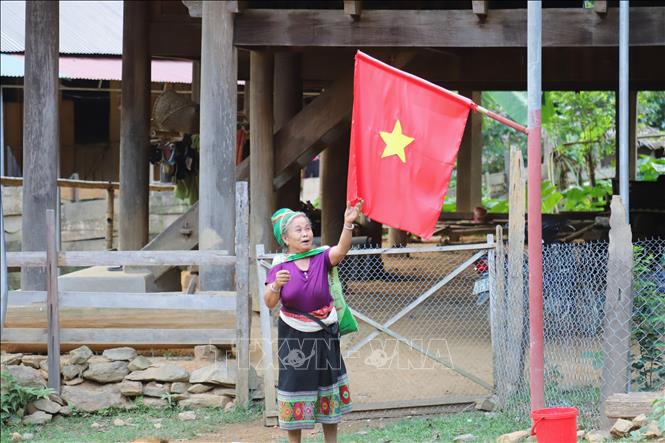 Người dân bản Na Ngân treo cờ Tổ quốc trên con đường liên bản. Ảnh: Xuân Tiến - TTXVN 