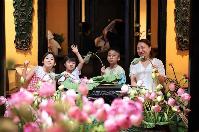 Nhiều gia đình cho trẻ nhỏ đến trải nghiệm ướp trà trong búp sen, góp phần lan tỏa nét đẹp văn hóa truyền thống tới thế hệ trẻ. Ảnh: Phạm Tuấn Anh - TTXVN