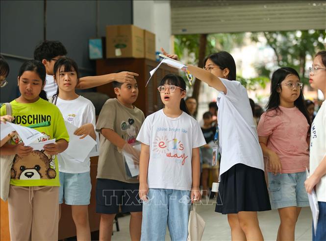 Hướng dẫn học sinh vào phòng thi. Ảnh: Thanh Tùng - TTXVN