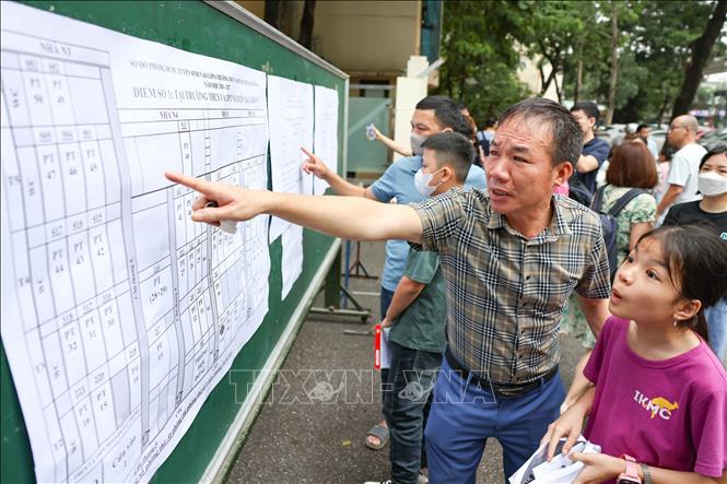 Phụ huynh cùng học sinh xem sơ đồ bố trí phòng thi. Ảnh: Thanh Tùng - TTXVN
