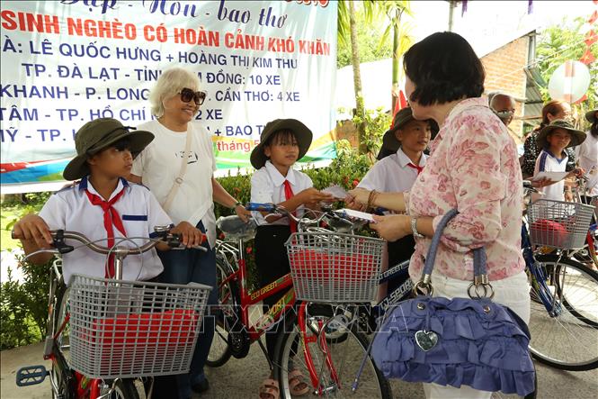 Nhà tài trợ tặng quà cho học sinh trong buổi khánh thành cây cầu mới. Ảnh: Duy Khương – TTXVN