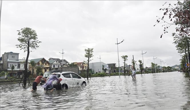 Có người phải đẩy xe ô tô do chết máy giữa đường vì ngập nước. Ảnh: Thanh Vân - TTXVN 