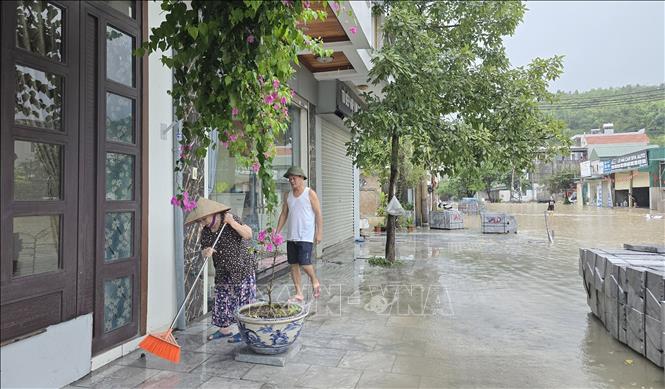 Người dân liên tục quét để ngăn nước tràn vào nhà. Ảnh: Thanh Vân - TTXVN 