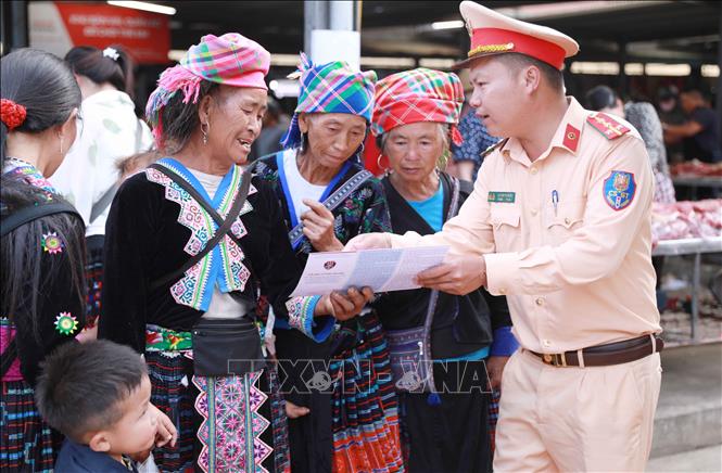 Cán bộ Đội số 1, Phòng Cảnh sát giao thông, Công an tỉnh Lai Châu xuống chợ phiên San Thàng phát tờ rơi và tuyên truyền cho người dân là đồng bào dân tộc thiểu số. Ảnh: Quý Trung – TTXVN