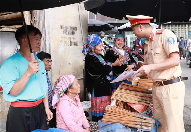 Cán bộ Đội số 1, Phòng Cảnh sát giao thông, Công an tỉnh Lai Châu xuống chợ phiên San Thàng phát tờ rơi và tuyên truyền cho người dân là đồng bào dân tộc thiểu số. Ảnh: Quý Trung – TTXVN