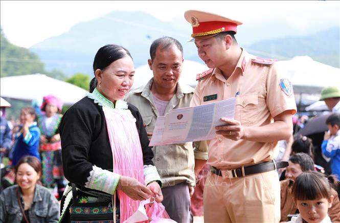 Cán bộ Phòng Cảnh sát giao thông, Công an tỉnh Lai Châu phát tờ rơi và tuyên truyền cho người dân là đồng bào dân tộc thiểu số. Ảnh: Quý Trung – TTXVN