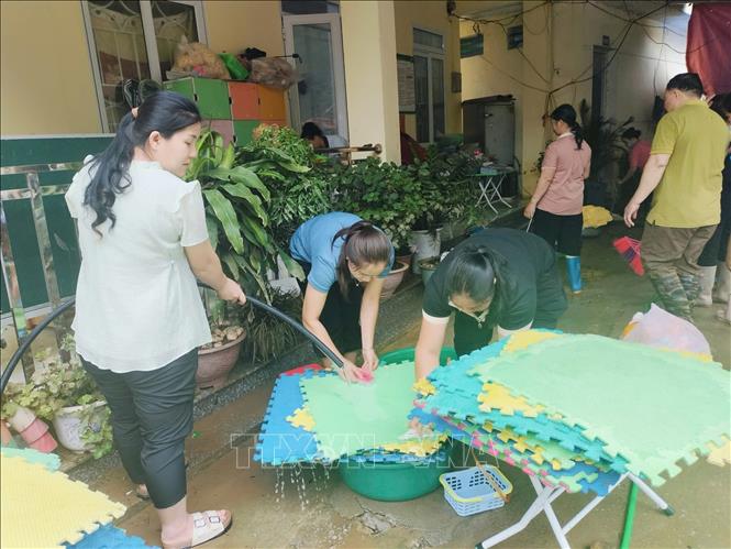 Giáo viên Trường Mầm non và Tiểu học Minh Long khẩn trương khắc phục hậu quả mưa lũ. Ảnh: TTXVN phát