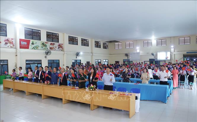 Các đại biểu và học sinh vẫy cờ thể hiện tình đoàn kết đặc biệt Việt Nam - Lào. Ảnh: Xuân Tú - PV TTXVN tại Lào