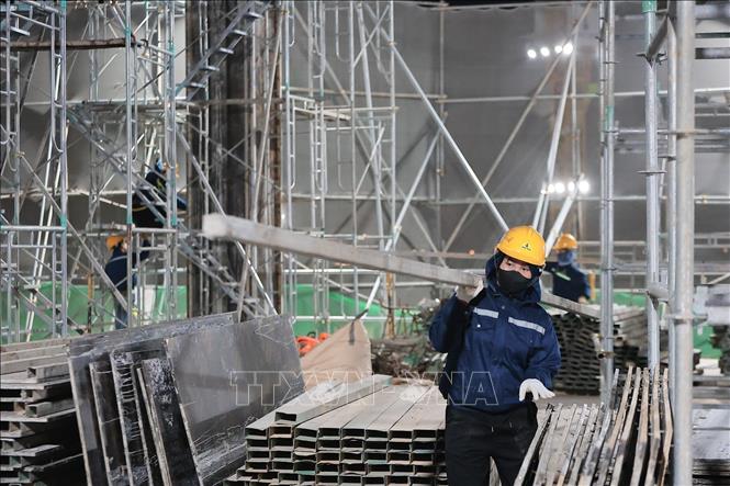 Công nhân vận chuyển vật liệu phục vụ thi công hạng mục khán đài tại công trường Sân vận động Hùng Vương trong đêm. Ảnh: Lê Đông - TTXVN 