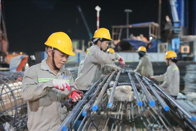 Công nhân thi công buộc thép cột trong điều kiện làm việc xuyên đêm tại công trường. Ảnh: Lê Đông - TTXVN 