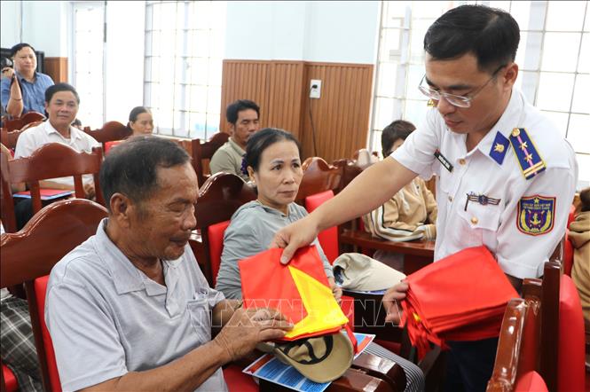 Cảnh sát biển tặng cờ tổ quốc cho ngư dân. Ảnh: Đinh Hương - TTXVN