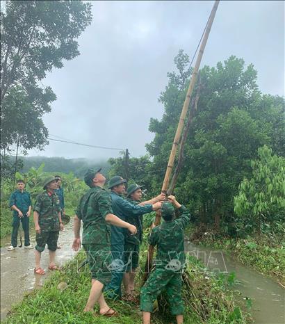 Cán bộ, chiến sĩ Đồn Biên phòng Quảng Đức chằng chống lại các cây, cột bị ngã đổ do mưa lớn. Ảnh: TTXVN phát 