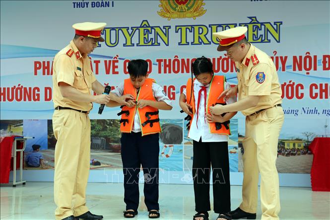Cảnh sát giao thông đường thủy thuộc Thủy đoàn I, Cục Cảnh sát giao thông (Bộ Công an) tuyên truyền, hướng dẫn cách mặc áo phao đúng cách cho học sinh Trường THCS Hà An, phường Hà An, tỉnh Quảng Ninh. Ảnh: Đức Hiếu - TTXVN