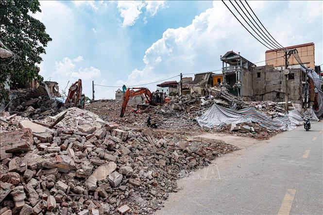 Máy xúc được huy động tháo dỡ công trình trong khu vực đường Cổ Nhuế, đẩy nhanh tiến độ giải phóng mặt bằng đoạn tuyến từ đường Phạm Văn Đồng đến sông Nhuệ. Ảnh: Phạm Tuấn Anh - TTXVN