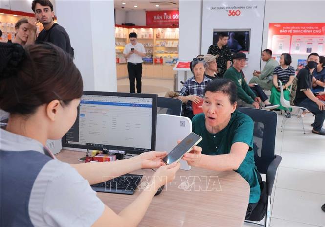 Nhân viên cửa hàng Viettel - 53 Lương Văn Can (Hà Nội) hỗ trợ khách hàng lớn tuổi xác thực thuê bao chính chủ. Ảnh: Hoàng Hiếu - TTXVN