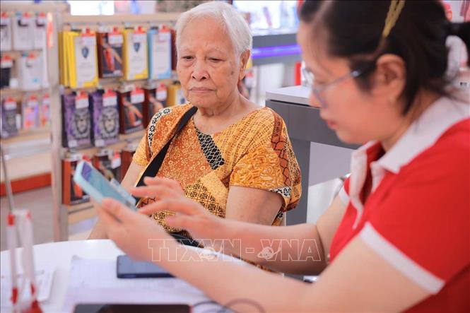 Nhân viên Viettel hỗ trợ bà Mai Thị Hồng Châu, 82 tuổi  (Hà Nội) xác thực thông tin thuê bao chính chủ. Ảnh: Hoàng Hiếu - TTXVN