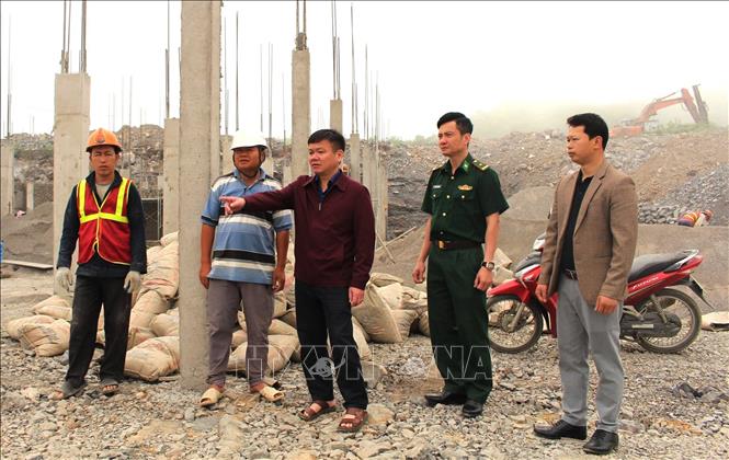 Bí thư Đảng ủy xã Sơn Vĩ Nguyễn Huy Sắc (giữa) kiểm tra tiến độ xây dựng trường Phổ thông Nội trú liên cấp Tiểu học và THCS Sơn Vĩ (Tuyên Quang) tại khu vực biên giới thường xuyên có sương mù, khí hậu khắc nghiệt. Ảnh: Minh Tâm - TTXVN