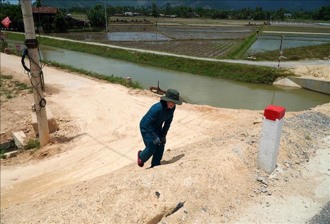 Cầu vượt ĐH35 đưa vào sử dụng đã “bít kín” đường dân sinh hiện hữu, người dân phải leo từng bậc trên taluy đất cao để đi lại. Ảnh: Lê Phước Ngọc-TTXVN
