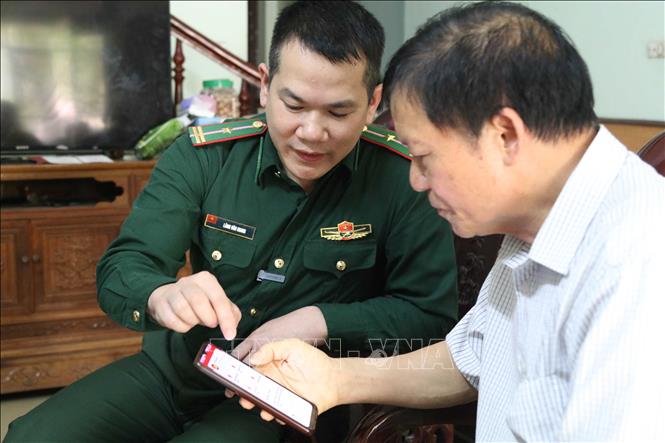 Cán bộ Đồn Biên phòng cửa khẩu Chi Ma, tỉnh Lạng Sơn, hướng dẫn người dân xã Mẫu Sơn sử dụng các ứng dụng số trên điện thoại thông minh. Ảnh: Quang Duy – TTXVN