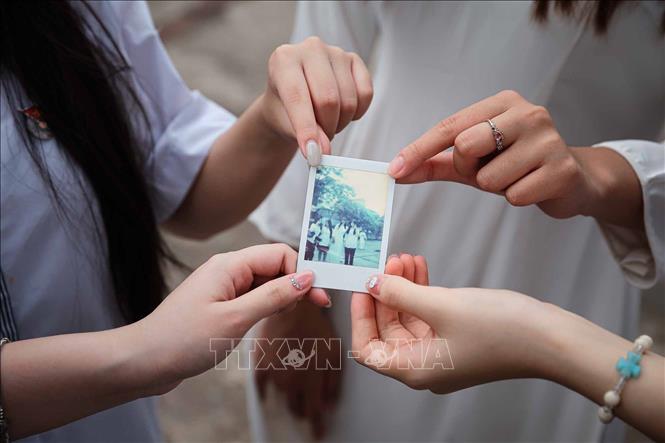 Tấm ảnh lấy ngay được các em học sinh nâng niu như giữ một lát cắt nhỏ của thanh xuân. Ảnh: Phạm Tuấn Anh - TTXVN