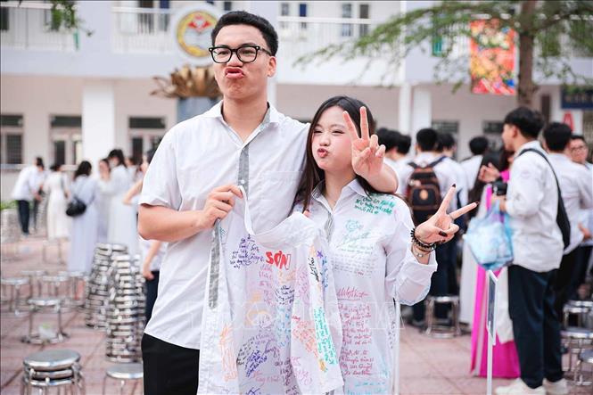 Tạo dáng vui nhộn cùng chiếc áo đầy chữ ký lưu niệm của bạn bè. Ảnh: Phạm Tuấn Anh - TTXVN