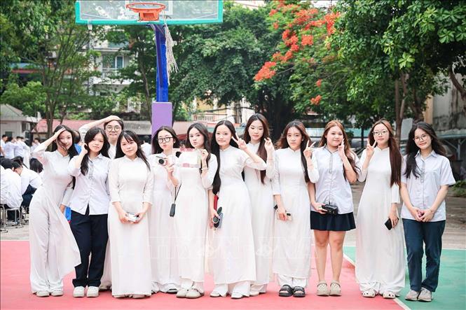Những tà áo dài trắng nổi bật giữa sắc đỏ hoa phượng, tạo nên khung cảnh quen thuộc của mùa chia tay học trò Hà Nội. Ảnh: Phạm Tuấn Anh - TTXVN