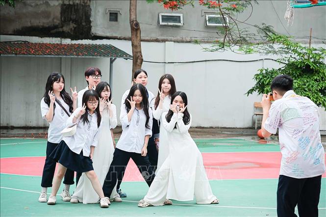 Tranh thủ tạo dáng bên sân bóng, lưu lại những khoảnh khắc cuối cùng của tuổi học trò dưới tán phượng đầu hè. Ảnh: Phạm Tuấn Anh - TTXVN