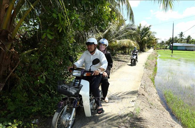 Phó Bí thư Đảng ủy, Chủ tịch UBND xã Đào Thị Loan Anh (ngồi sau) đi công tác tất cả các ấp của xã bằng xe gắn máy. Ảnh: Duy Khương – TTXVN 