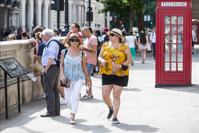 Khách du lịch di chuyển trên đường phố trong thời tiết nắng nóng tại London, Anh. Ảnh: THX/TTXVN