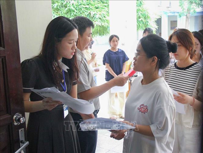 Cán bộ coi thi gọi thí sinh vào phòng thi (điểm thi Trường Đại học Sư phạm Hà Nội). Ảnh: TTXVN