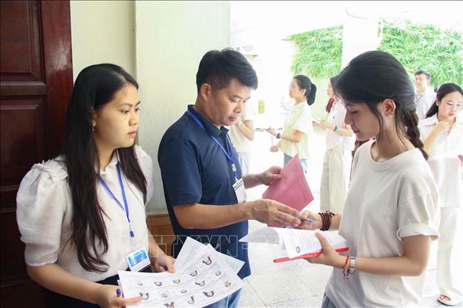 Cán bộ coi thi gọi thí sinh vào phòng thi (điểm thi Trường Đại học Sư phạm Hà Nội). Ảnh: TTXVN