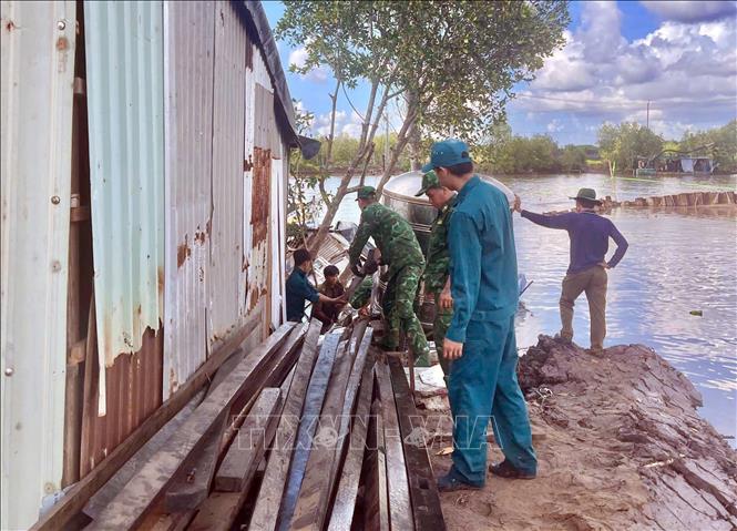 Cán bộ chiến sĩ Đồn Biên phòng Năm Căn (Cà Mau) hỗ trợ các hộ dân di dời tài sản sau sạt lở. Ảnh: TTXVN phát.