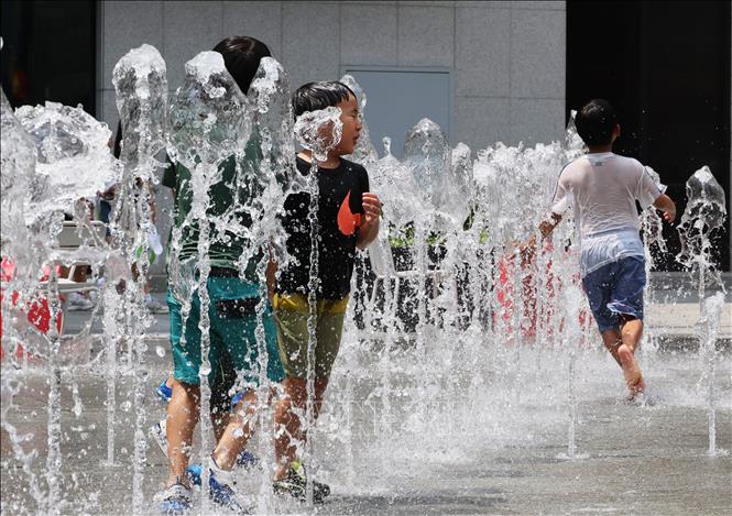 Các em nhỏ chơi đùa bên đài phun nước để tránh nóng tại Seoul, Hàn Quốc. Ảnh: Yonhap/TTXVN