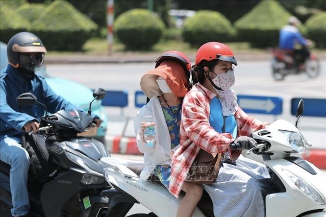 Người dân khi ra đường cần trang bị khăn, mũ, áo chống nắng… Ảnh: Minh Quyết - TTXVN