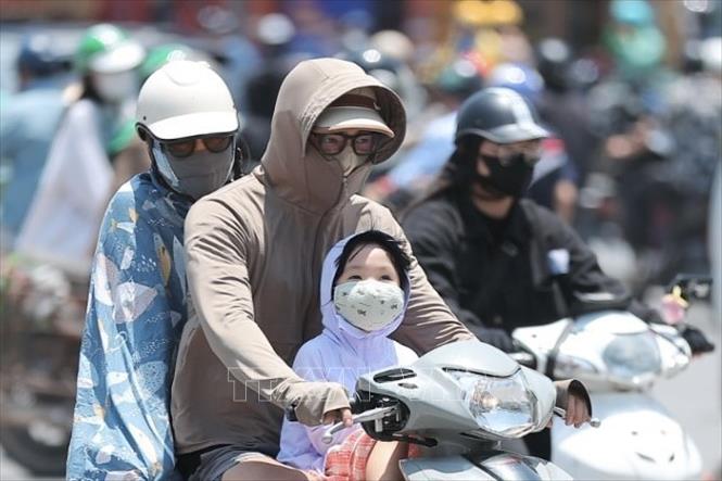 Người dân khi ra đường cần trang bị khăn, mũ, áo chống nắng… Ảnh: Minh Quyết - TTXVN