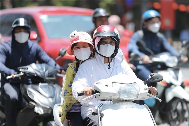 Người dân khi ra đường cần trang bị khăn, mũ, áo chống nắng… Ảnh: Minh Quyết - TTXVN