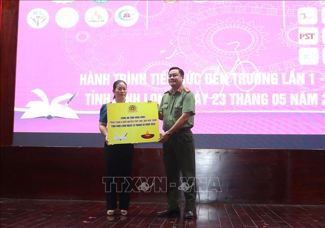 Trao bảng tượng trưng kinh phí hỗ trợ tập cho học sinh. Ảnh: Lê Thúy Hằng – TTXVN