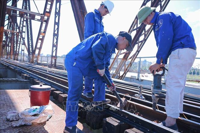 Công nhân đang triển khai bảo dưỡng hệ thống đường sắt trên cầu Long Biên giữa trưa nắng tới 40 độ. Ảnh: Hoàng Hiếu - TTXVN