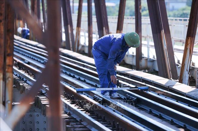 Dưới cái nóng tới 40 độ C, các công nhân vẫn cặm cụi, cẩn thận triển khai bảo dưỡng hệ thống đường sắt trên cầu Long Biên theo kế hoạch. Ảnh: Hoàng Hiếu - TTXVN