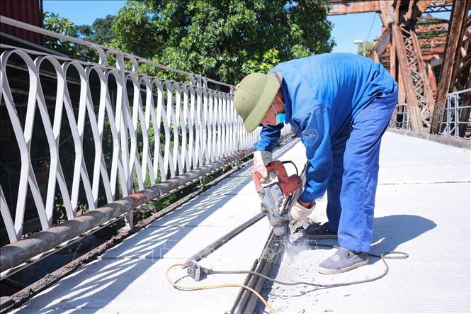 Giữa trưa 24/5, các công nhân vẫn khẩn trương hoàn thiện những công đoạn cuối trên mặt đường cầu Long Biên. Ảnh: Hoàng Hiếu - TTXVN